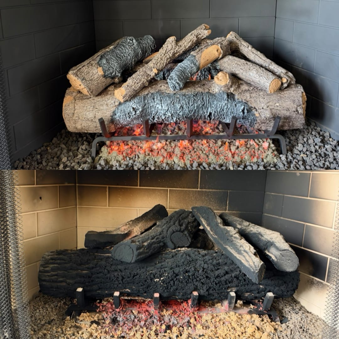 Gas fireplace log set covered in heavy black soot above a burner with faint red flames